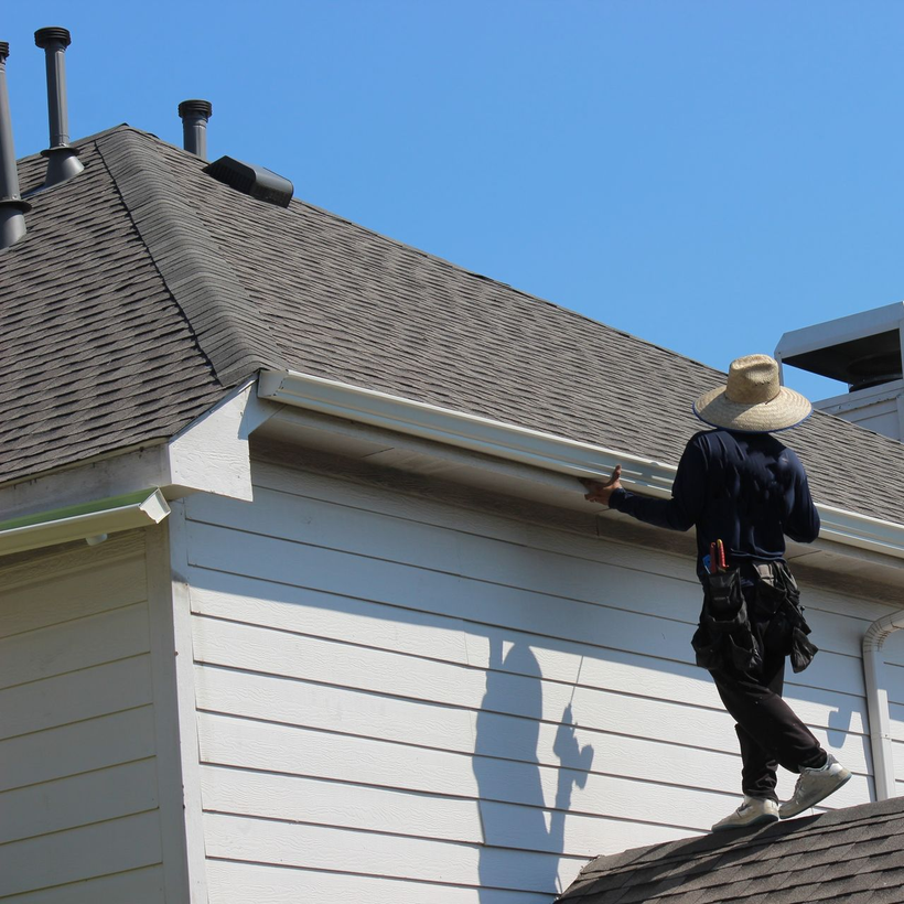 A man is working on the gutters of a house.