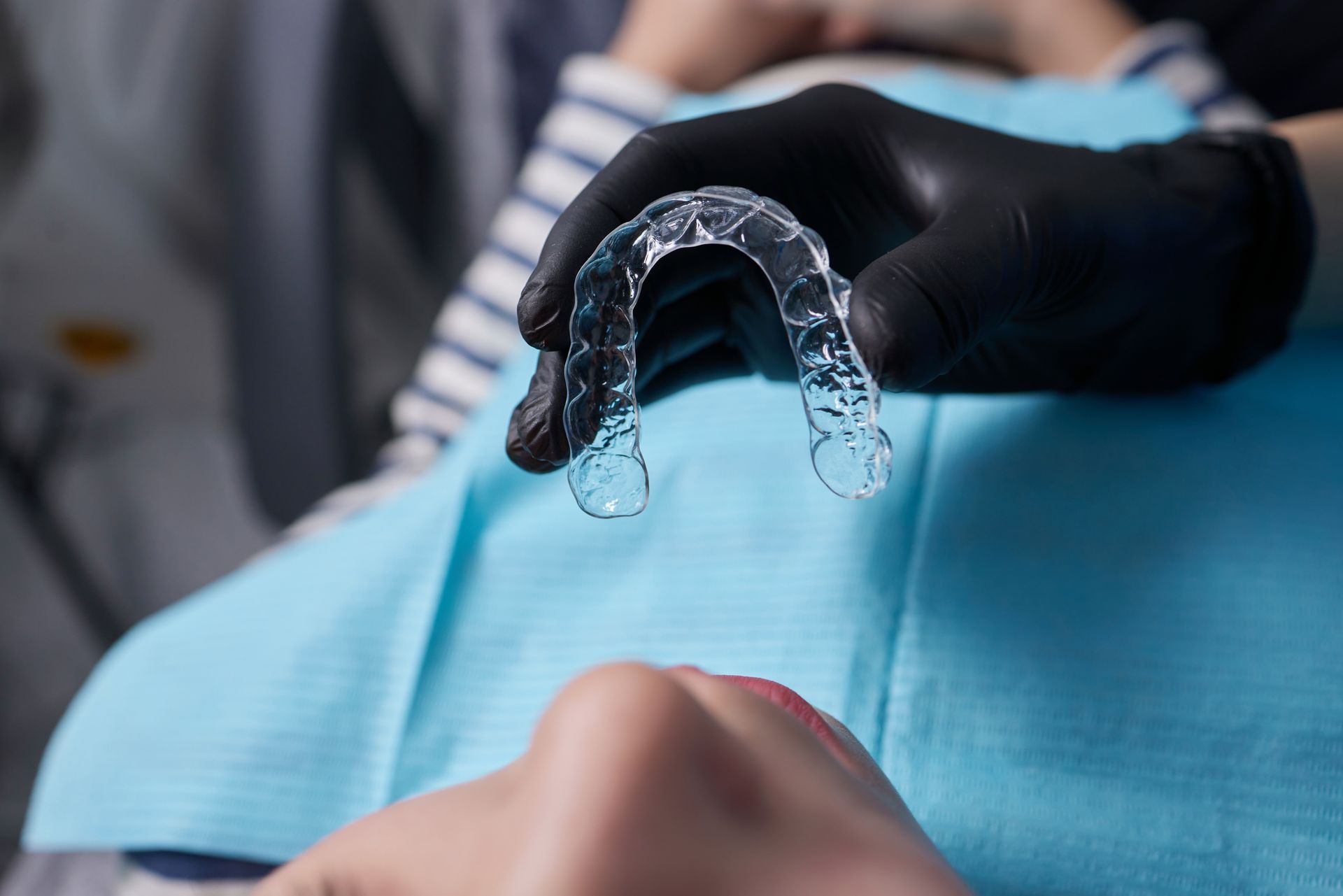 Un dentista tiene un apparecchio trasparente sui denti di un paziente.