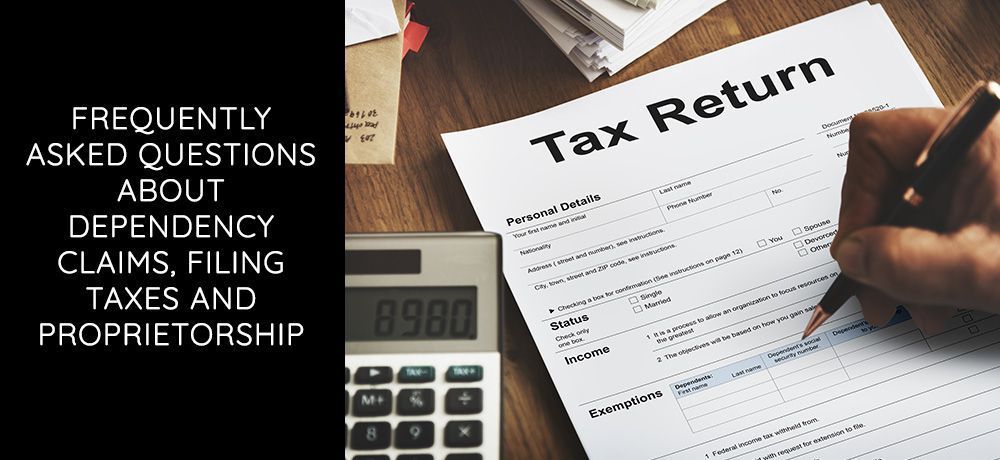 Person filling out a tax return form with a calculator and tax return papers on the table.