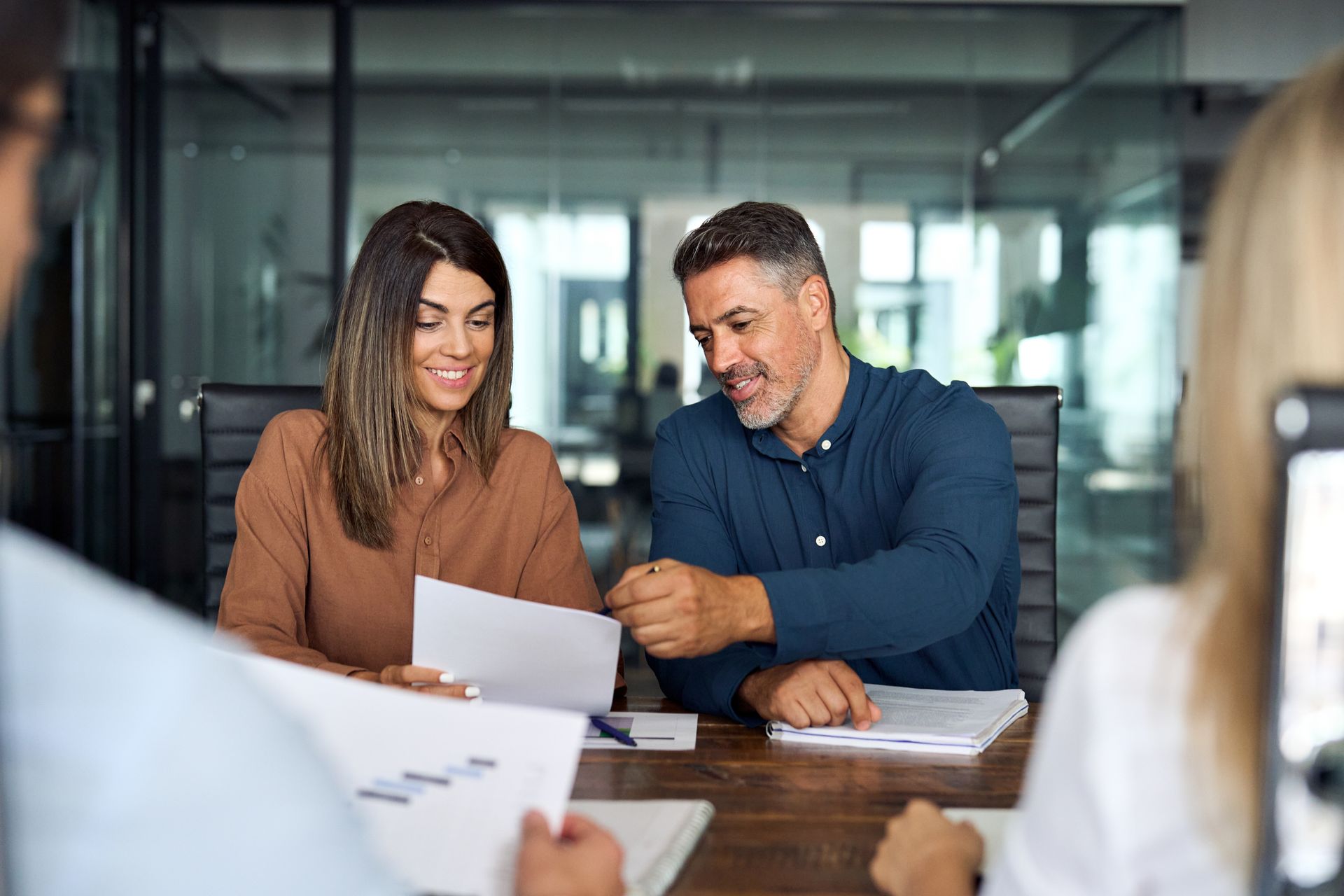 Business colleagues reviewing documents at a table in a modern office. Smiling and pointing.