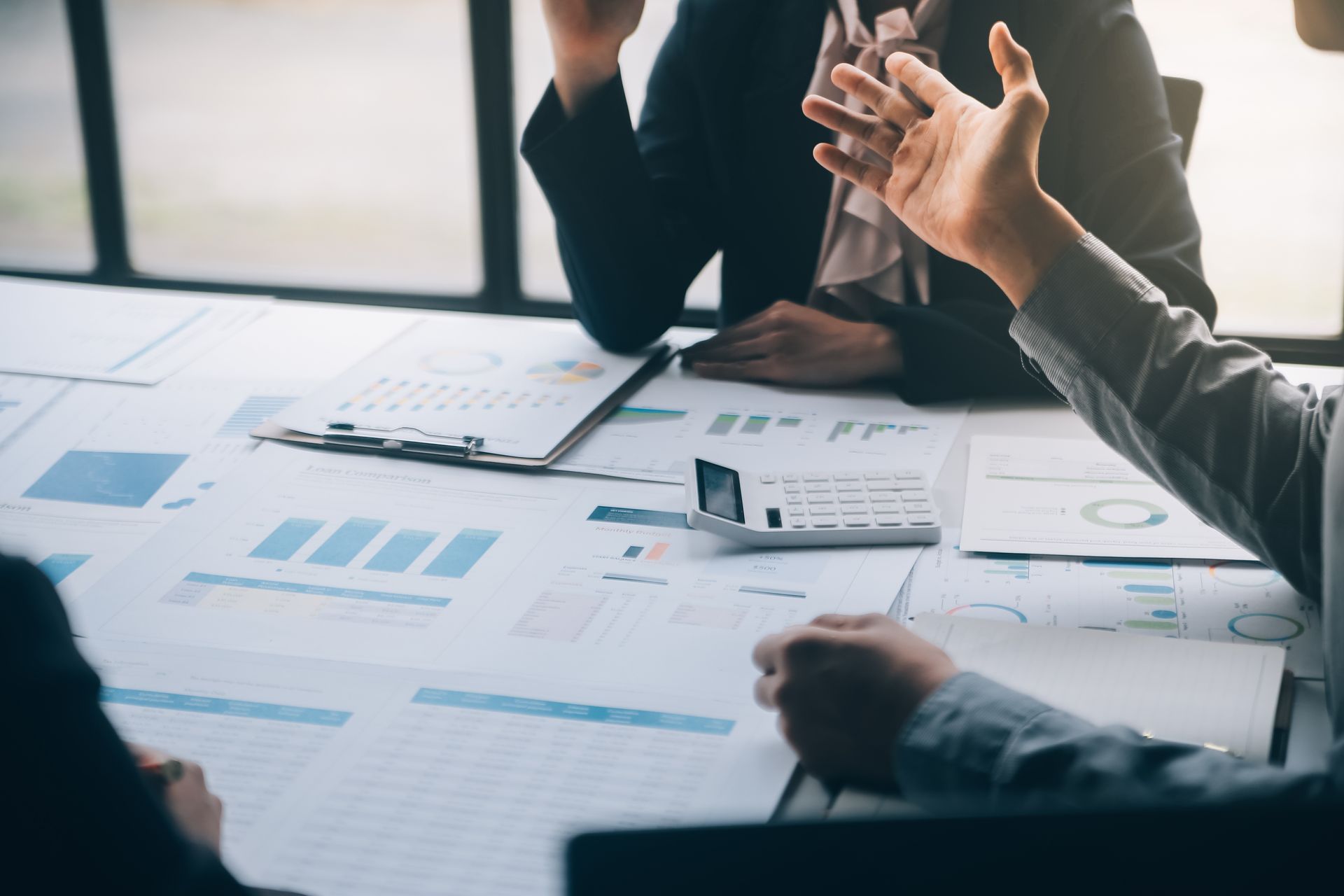 Business people reviewing charts and graphs, discussing finances at a table.