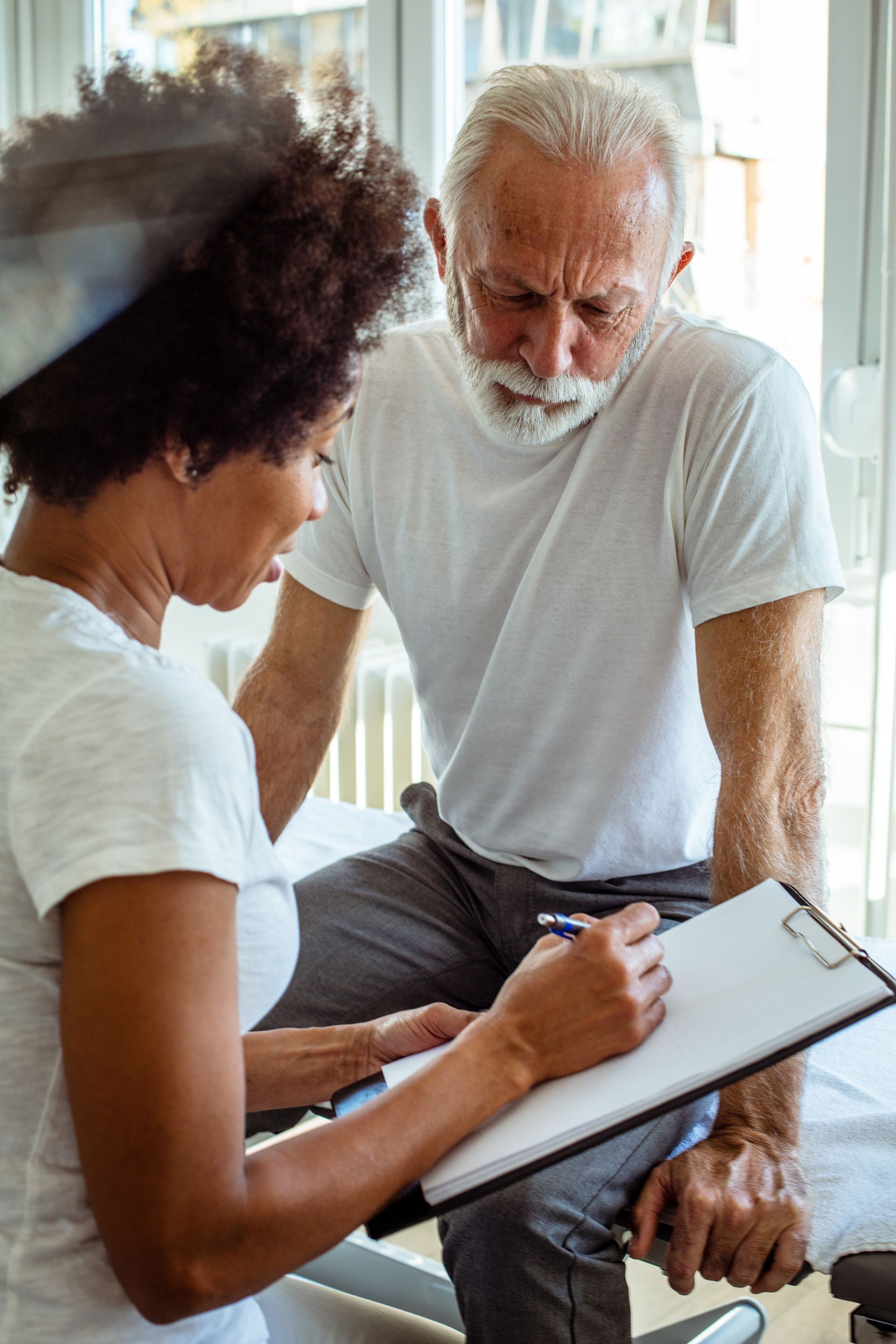 best chiropractor consultation with senior patient reviewing treatment plan on clipboard indoors.