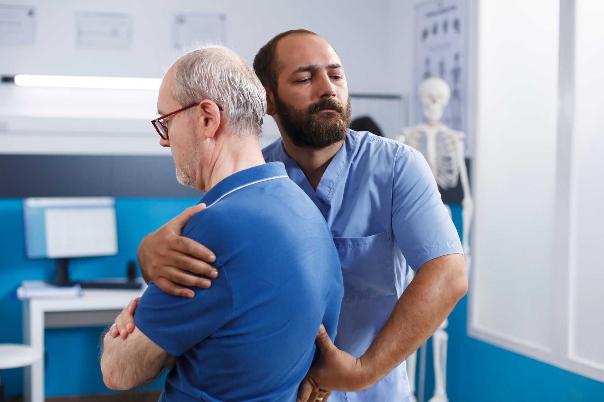 A chiropractor performing a spinal adjustment on an older male patient in a clinical exam room A chiropractor performing a spinal adjustment on an older male patient in a clinical exam room