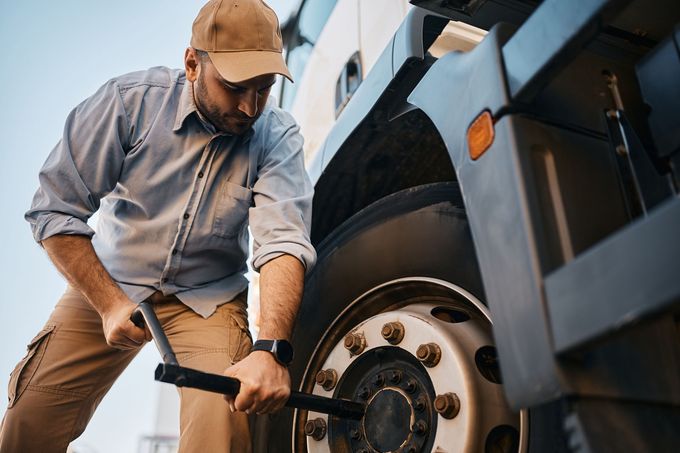 A man is changing a tire on a truck with a wrench.