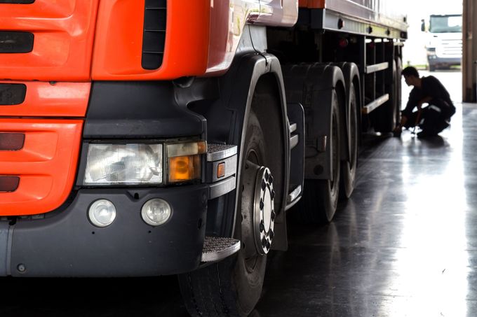 A man is working on a truck in a garage.