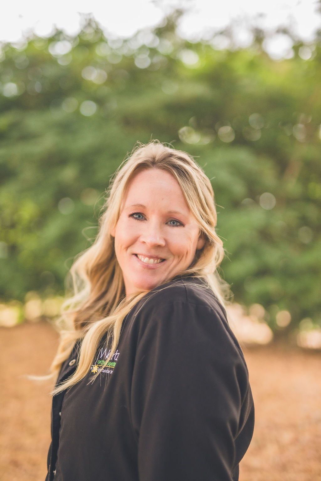 a woman in a black jacket is smiling for the camera .