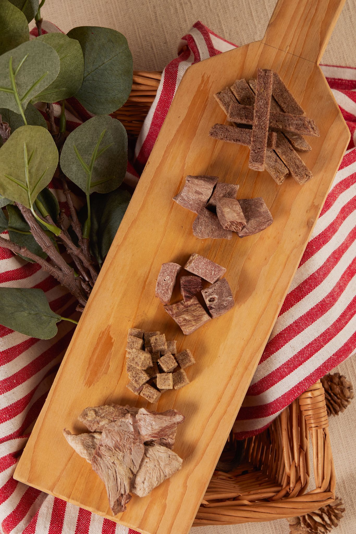 木板上放著五堆切成小方塊的乾肉，鋪在紅白條紋的布上。