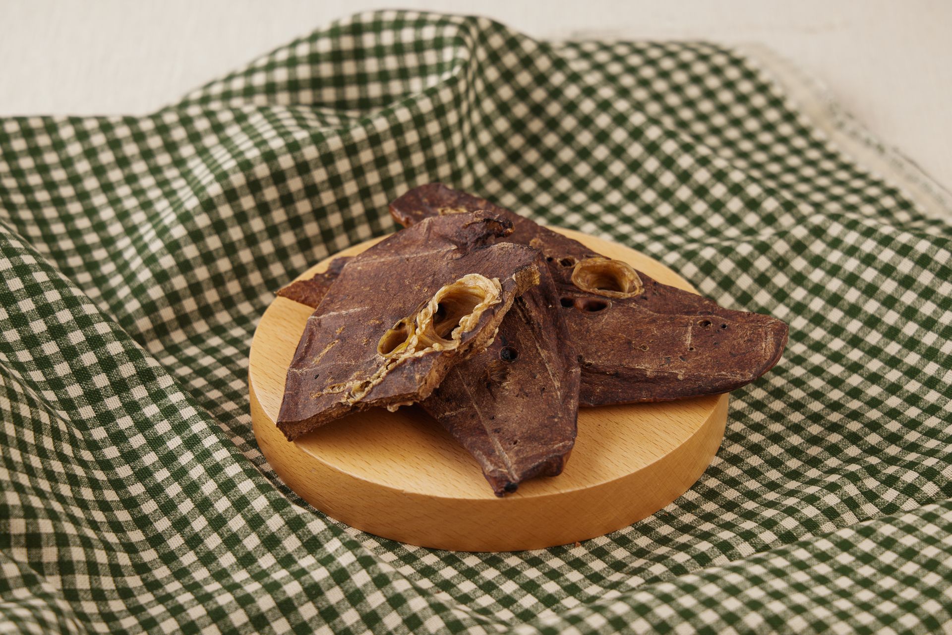 肉乾放在鋪著綠白格子佈的木質杯墊上。