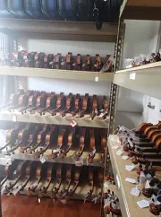 Rows of violins on shelves in a store, with many instruments lined up vertically and individual pieces on the foreground.