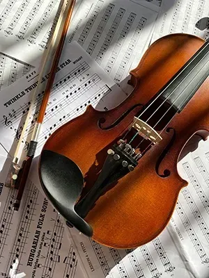 A wooden violin and a bow resting on top of several sheets of musical notation.