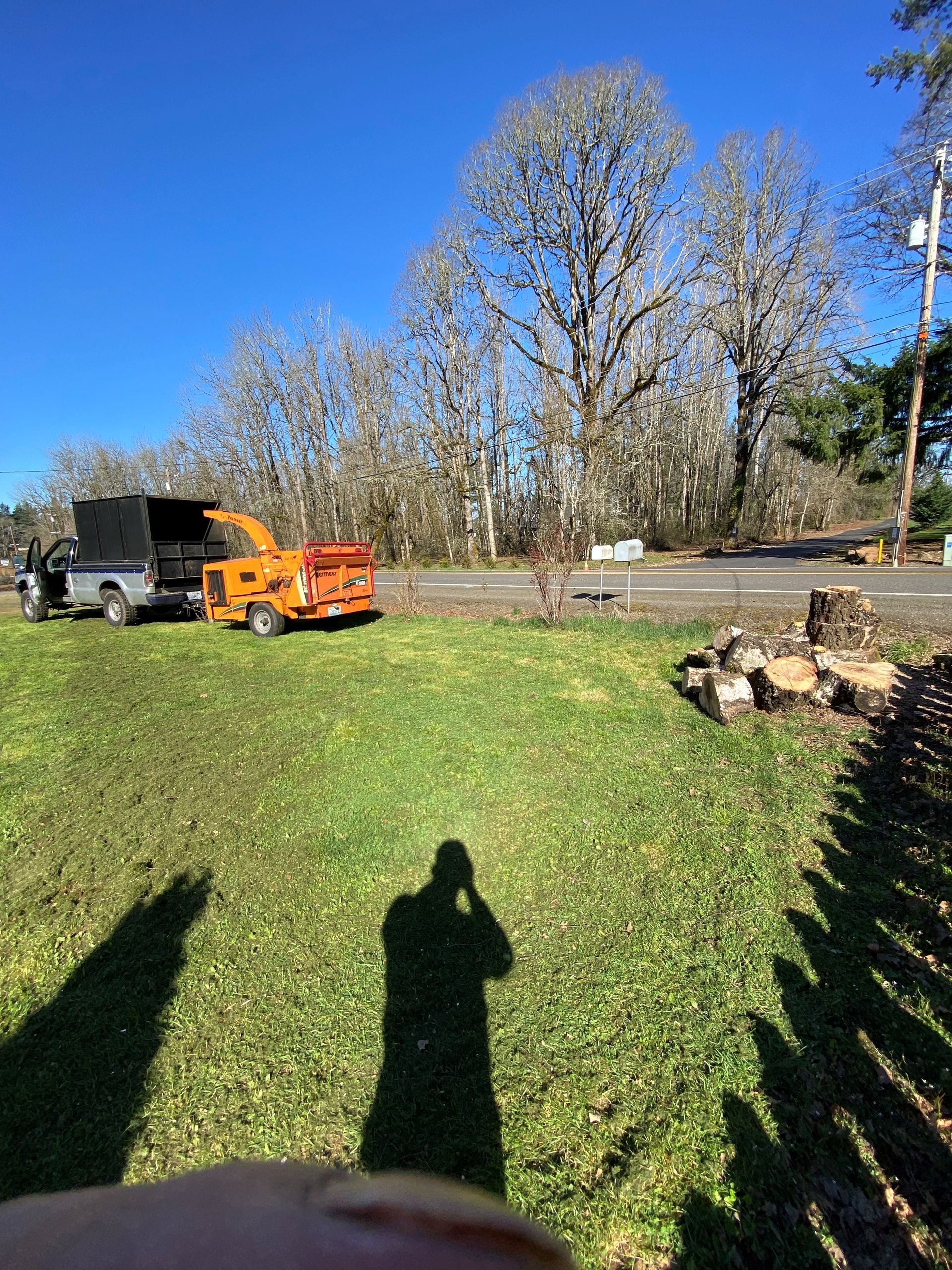 A person is taking a picture of a tree chipper in a field.