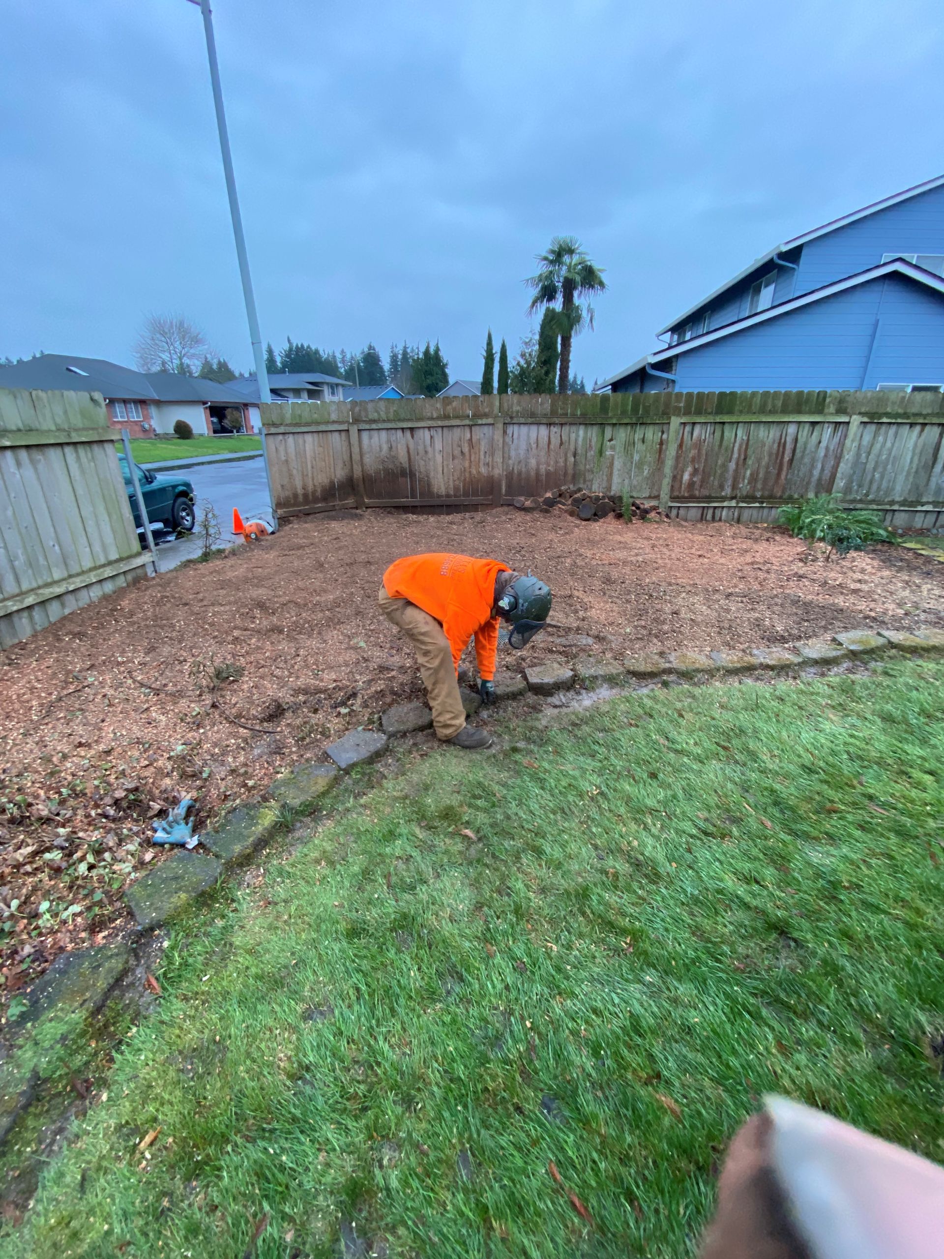 A man is working on a tree stump in a backyard.