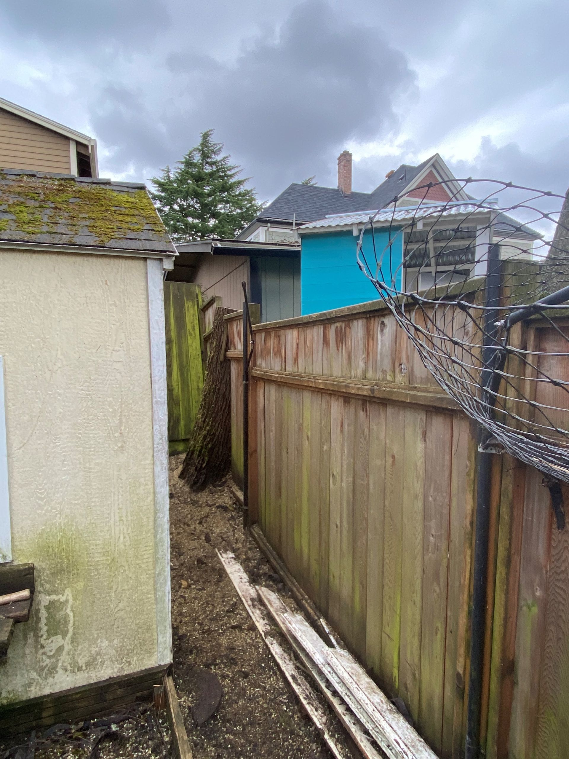 A wooden fence with barbed wire surrounding it and a shed in the background.