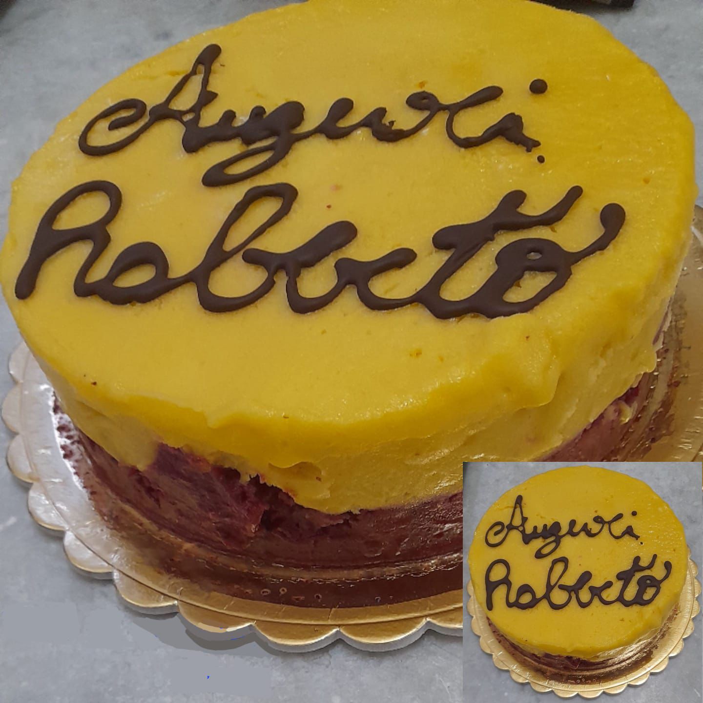 Una torta gialla con scritto auguri roberto sopra
