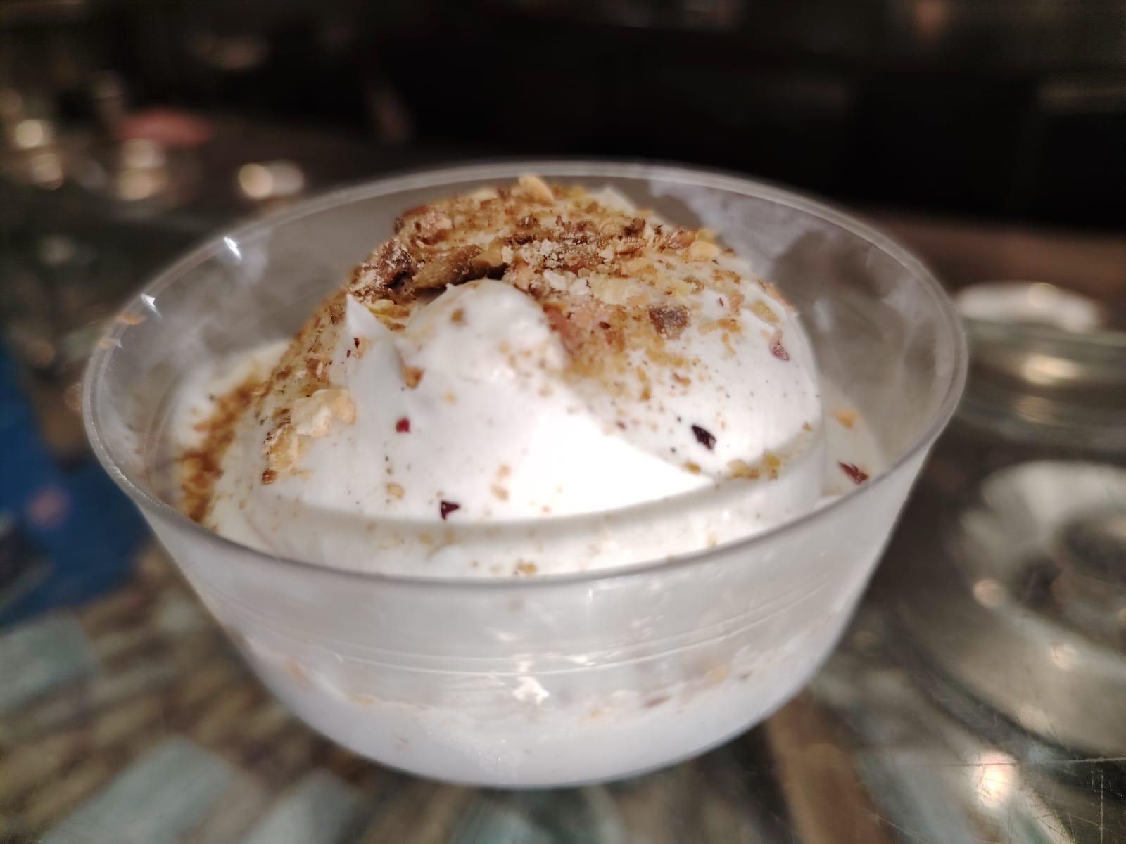 Una ciotola di gelato con sopra delle noci è su un tavolo.