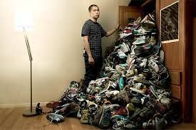 A man is standing in front of a pile of shoes.