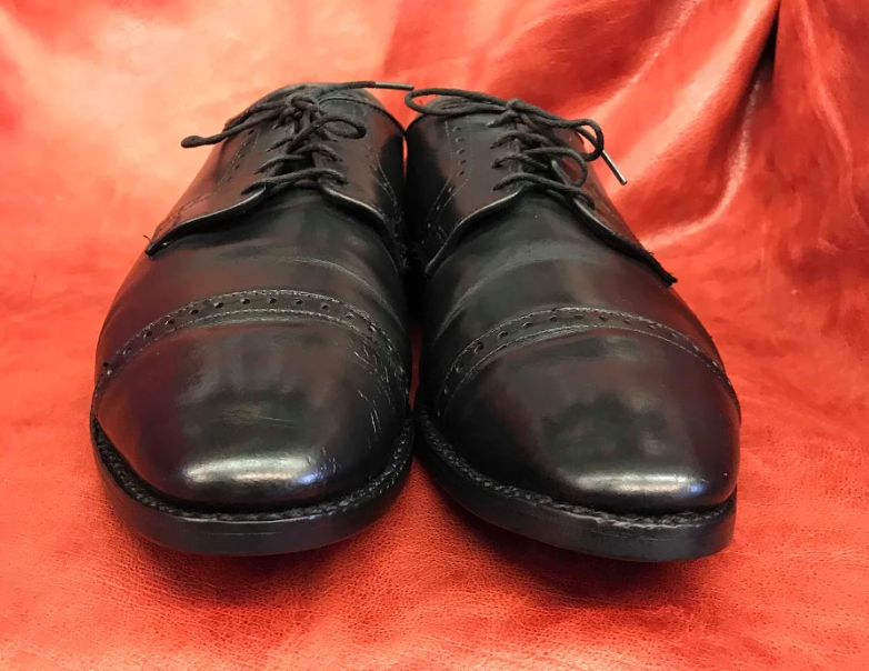 A pair of black shoes are sitting on a red cloth