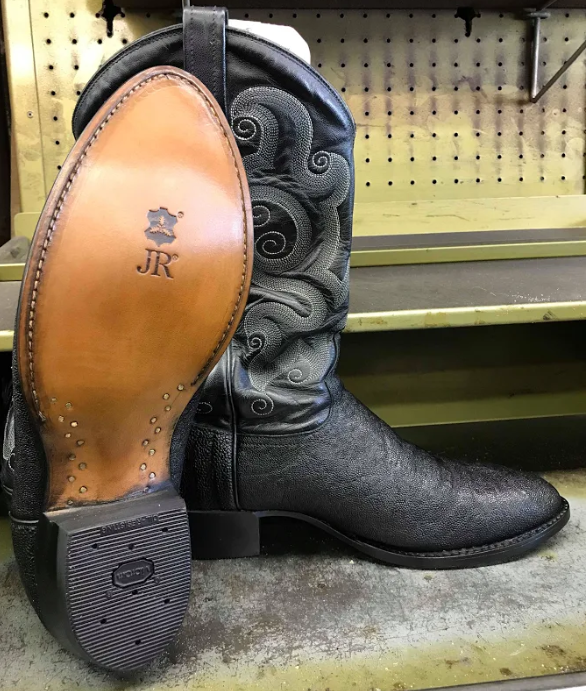 A pair of black cowboy boots with jr written on the sole