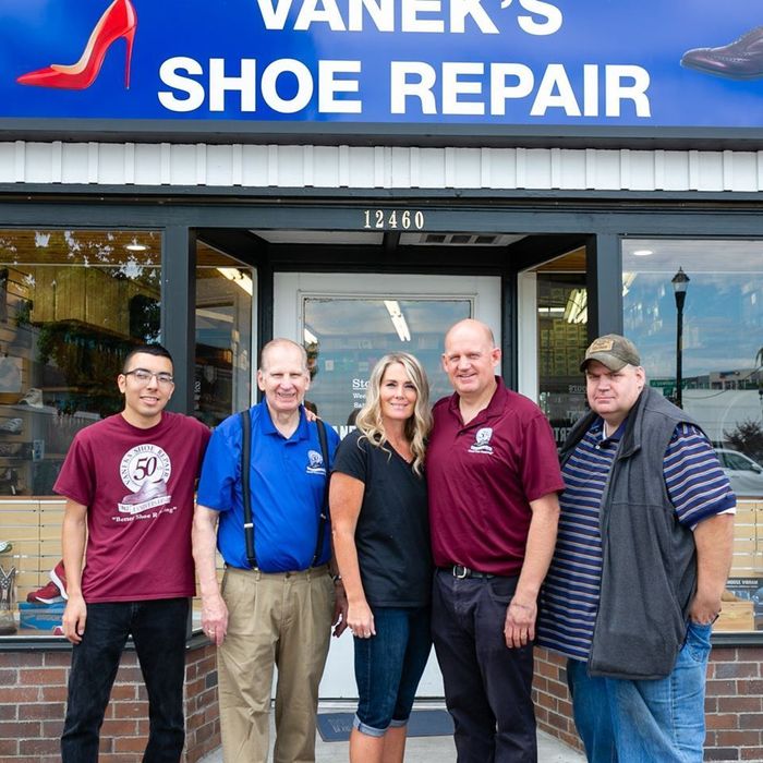 A group of people standing in front of vanek 's shoe repair