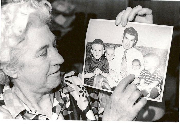 A woman holds up a black and white photo of her family