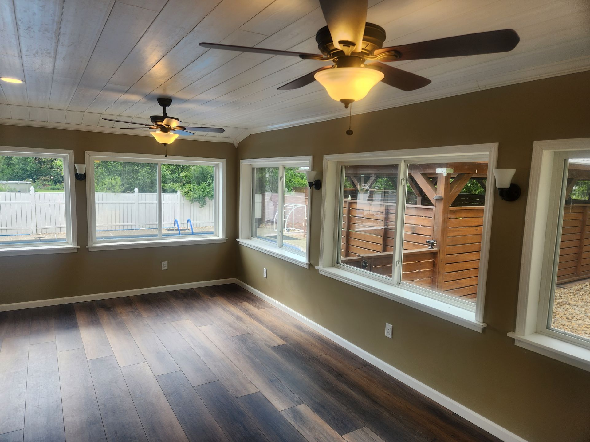 A living room with a ceiling fan and lots of windows