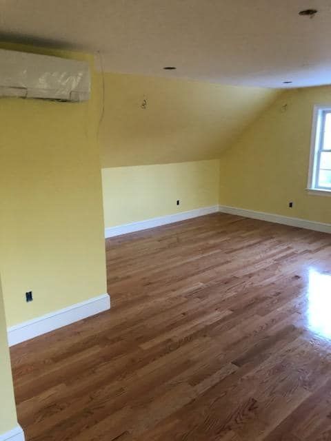 An empty room with yellow walls and hardwood floors