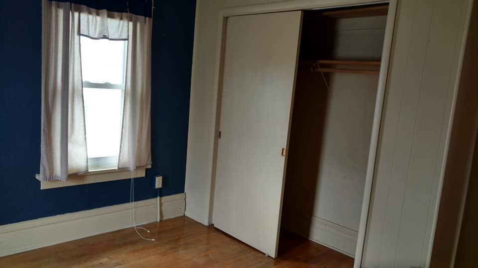An empty bedroom with a closet and a window.