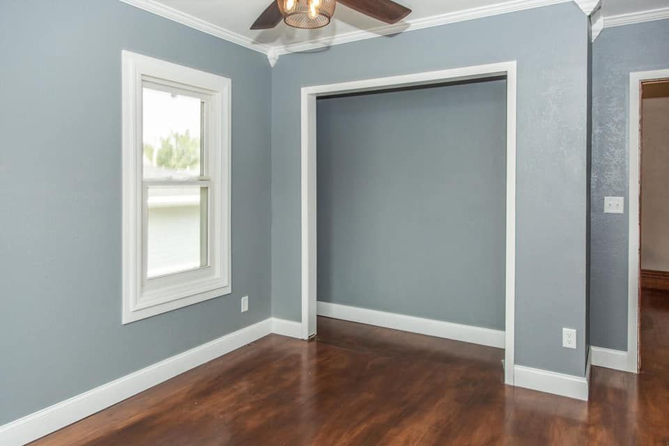 An empty room with a ceiling fan and a window.