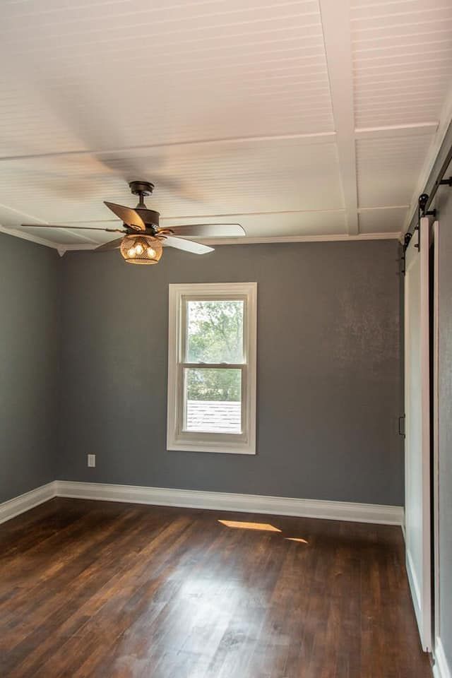An empty room with a ceiling fan and a window.