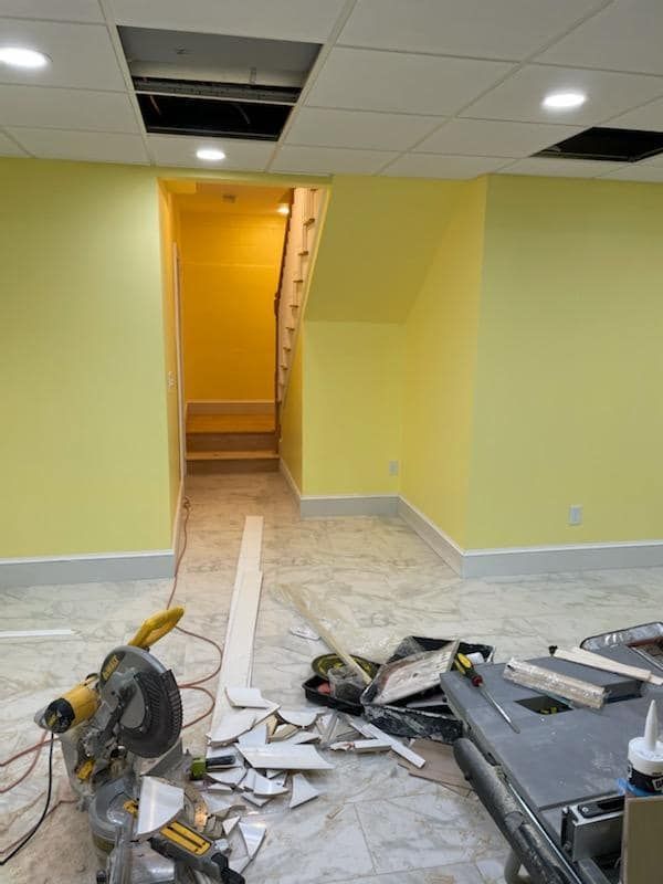A basement under construction with yellow walls and a staircase.