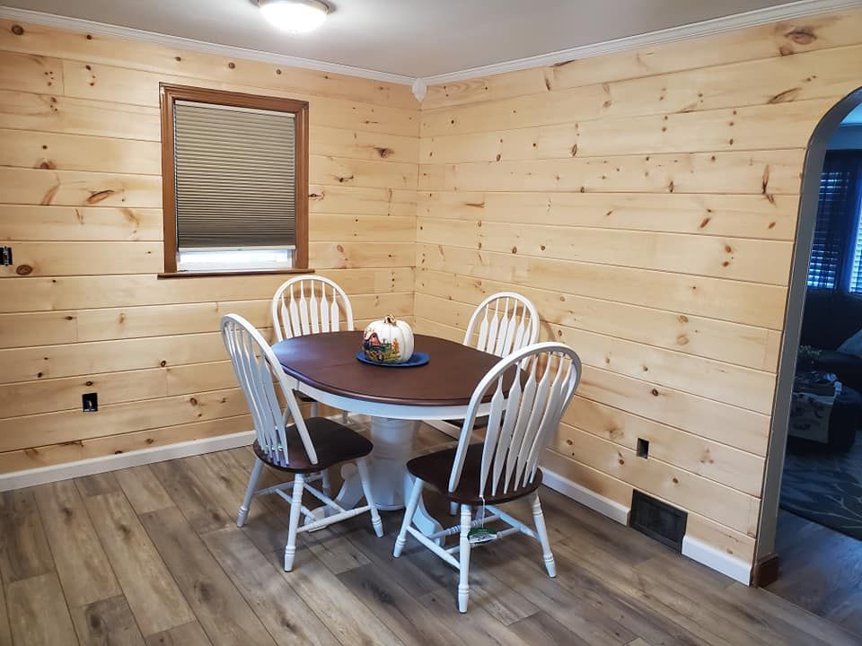 A dining room with a table and chairs in a log cabin.