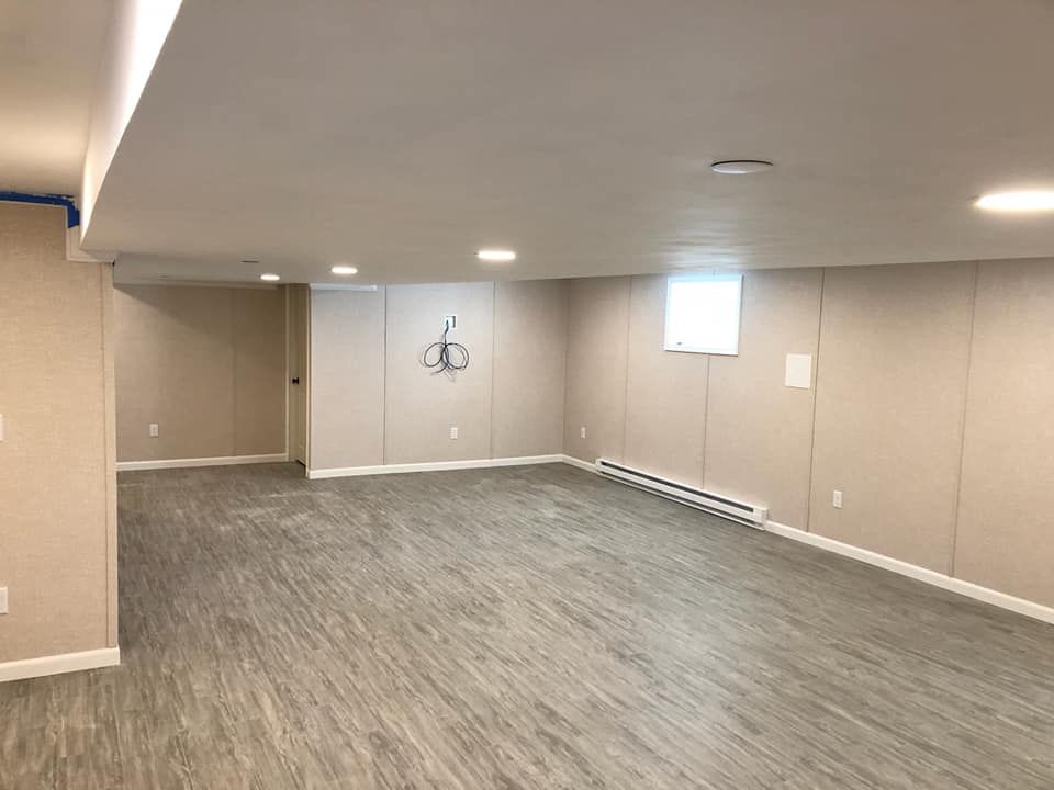 An empty basement with a wooden floor and beige walls.