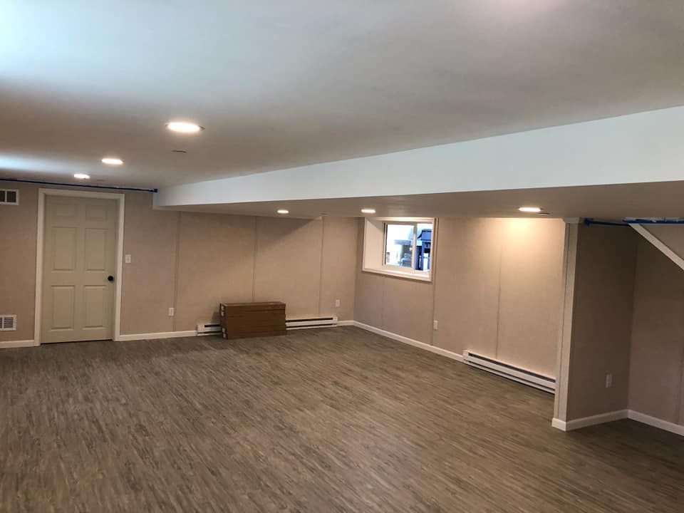 An empty basement with hardwood floors and a window.