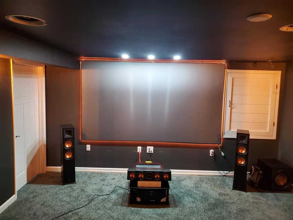 A home theater with a projector screen and speakers.