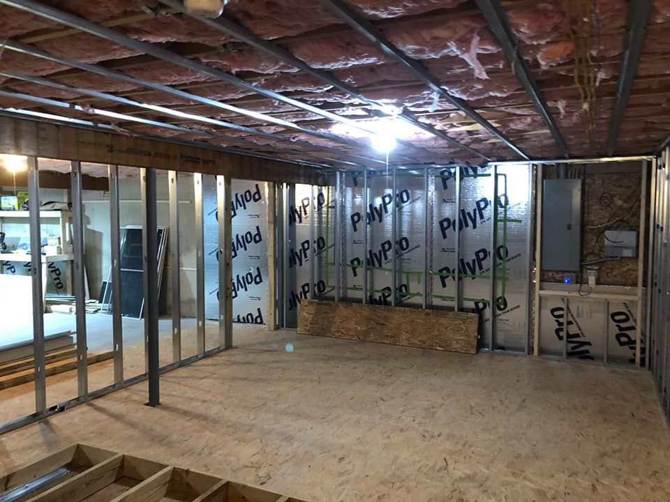 A basement under construction with insulation on the walls and ceiling.