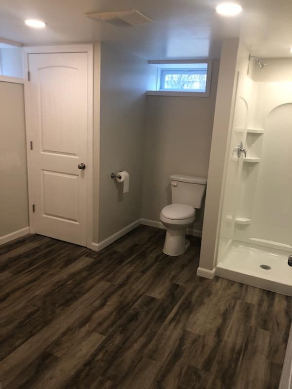 A bathroom with a toilet , shower and window.
