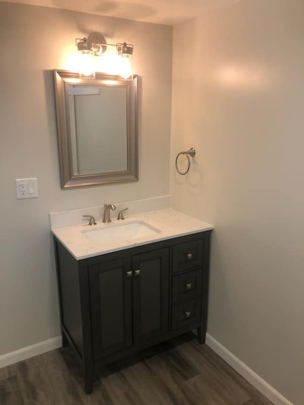 A bathroom with a sink , mirror and light.
