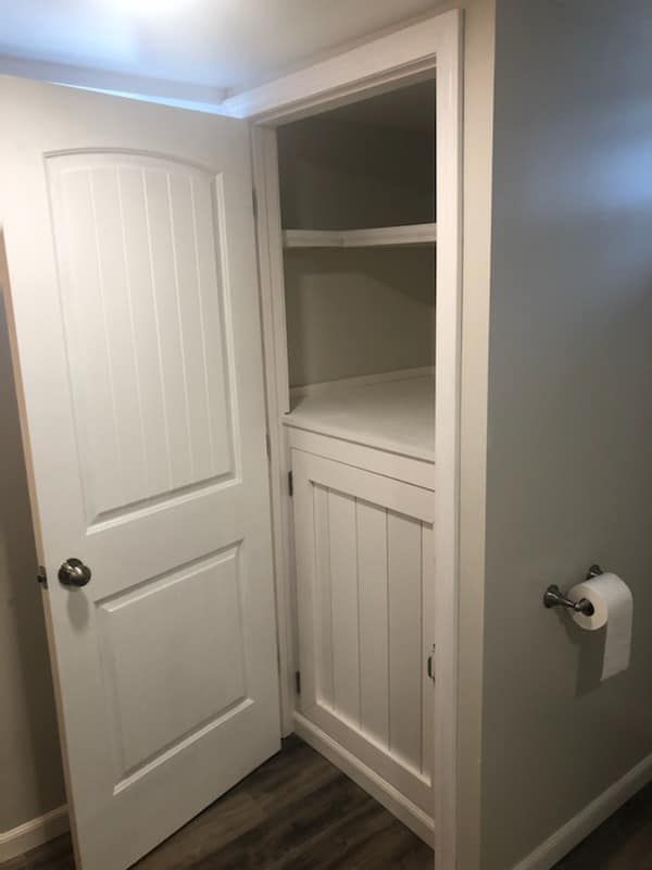 A bathroom with a closet and a toilet paper holder.