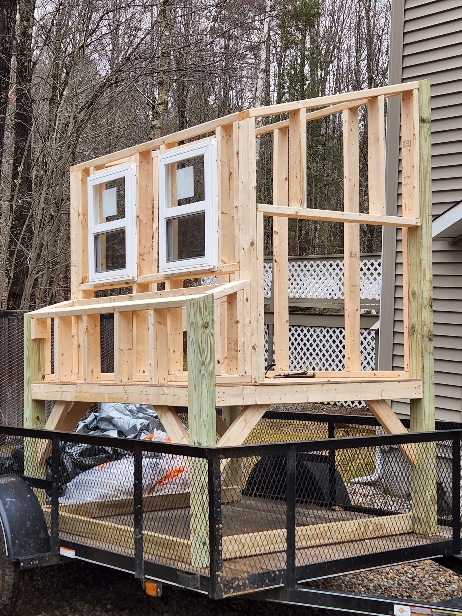 A wooden structure is being built on a trailer in front of a house.