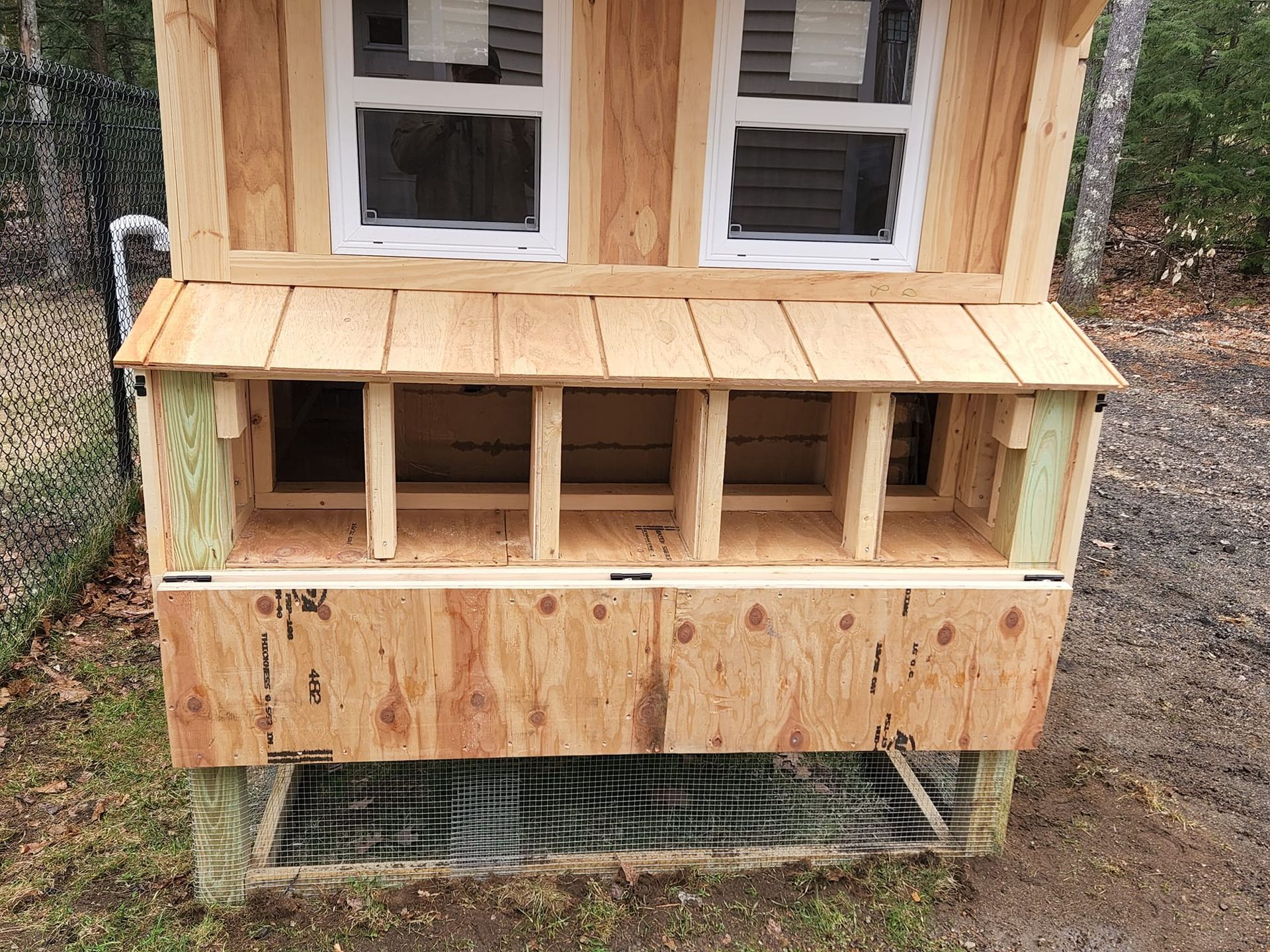 A wooden chicken coop is sitting on top of a dirt field.