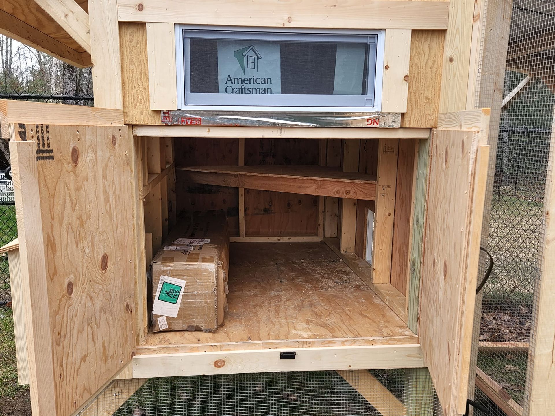 The inside of a wooden chicken coop with the doors open