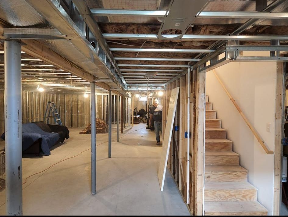 A basement under construction with stairs and a couch.