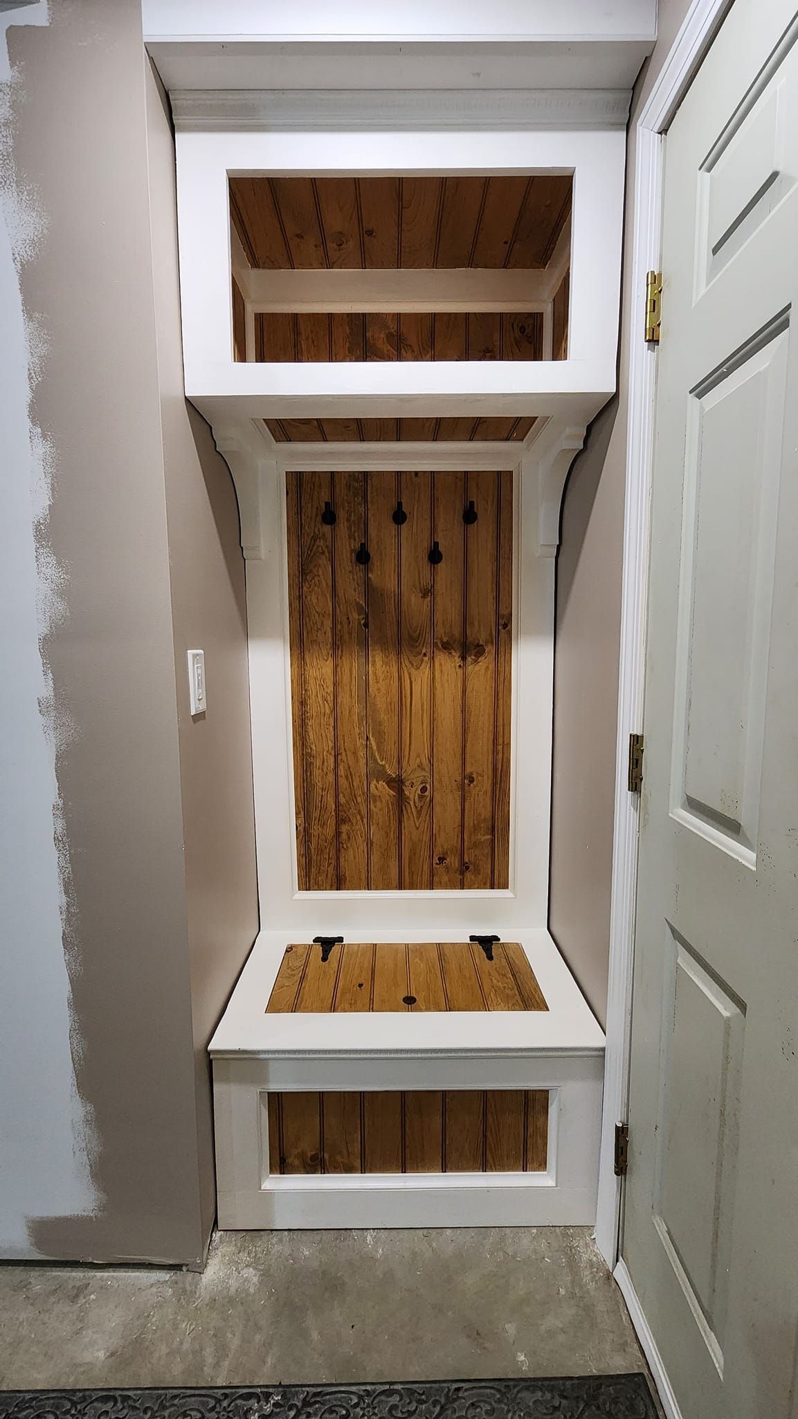 A corner of a room with a shelf and a door.