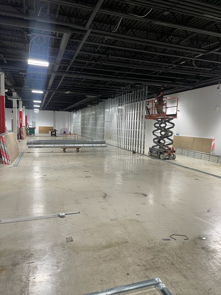 A large empty warehouse with a scissor lift in the middle of it.