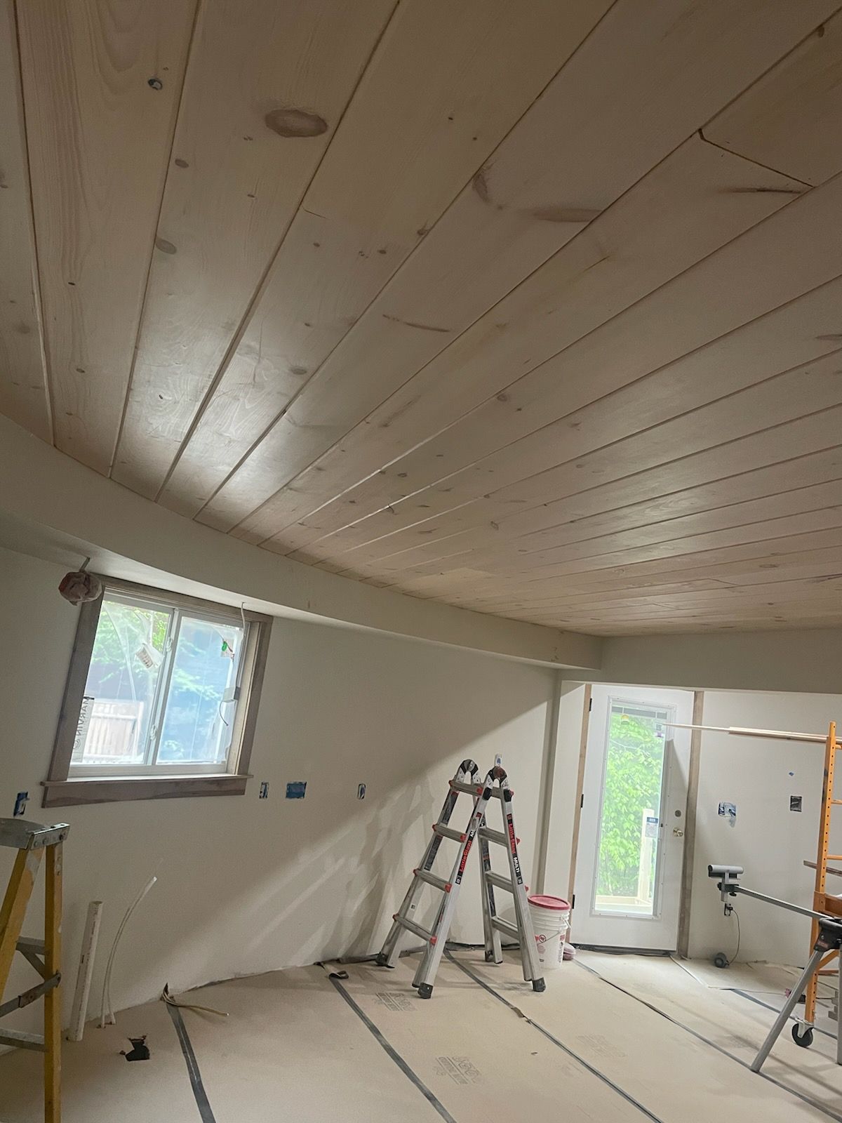 A room with a wooden ceiling and a ladder in it