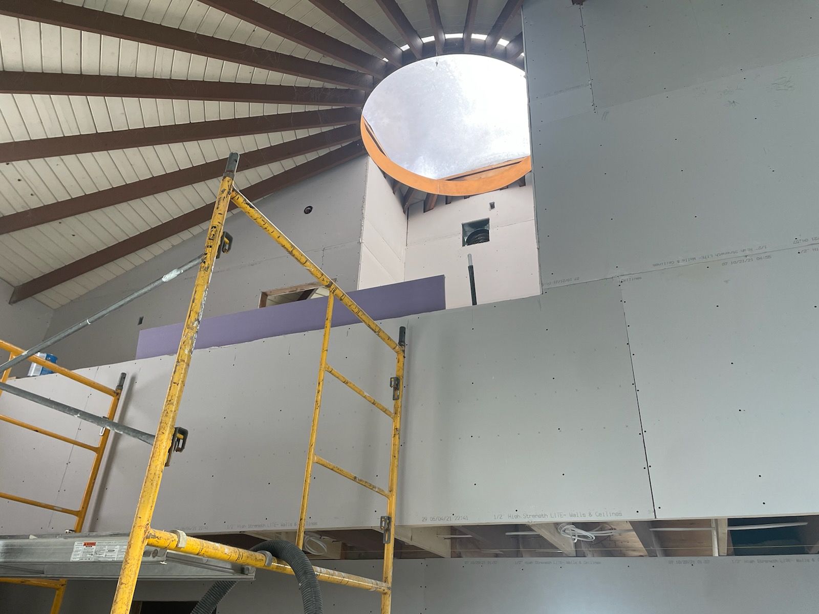 A scaffolding is sitting on top of a wall in a building under construction.