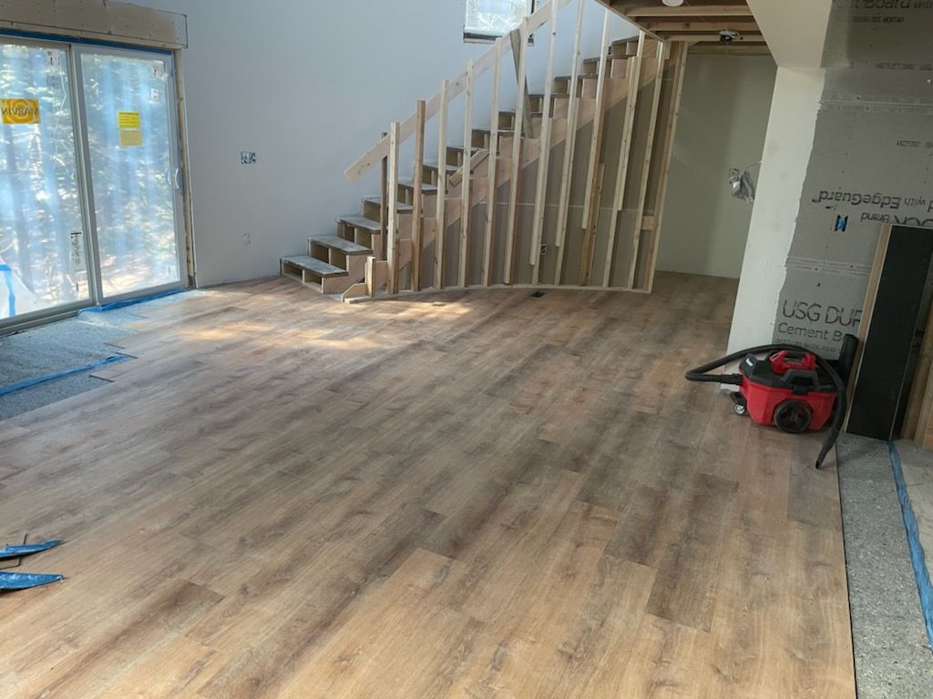 A room with hardwood floors and a staircase in the background.