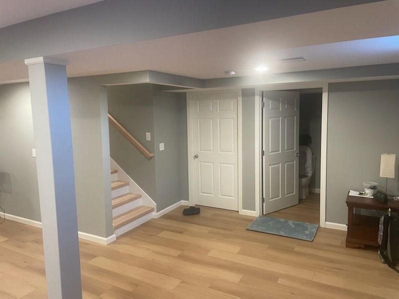 A basement with hardwood floors and stairs leading up to the second floor.