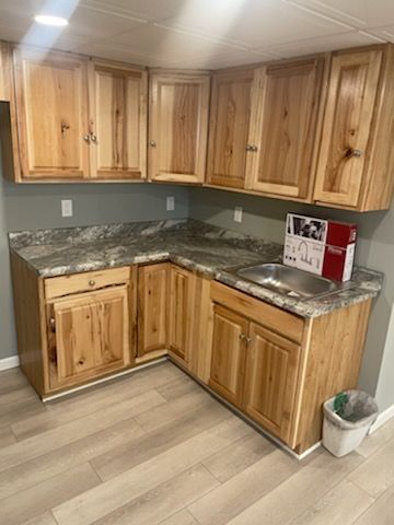 A kitchen with wooden cabinets , granite counter tops , and a sink.