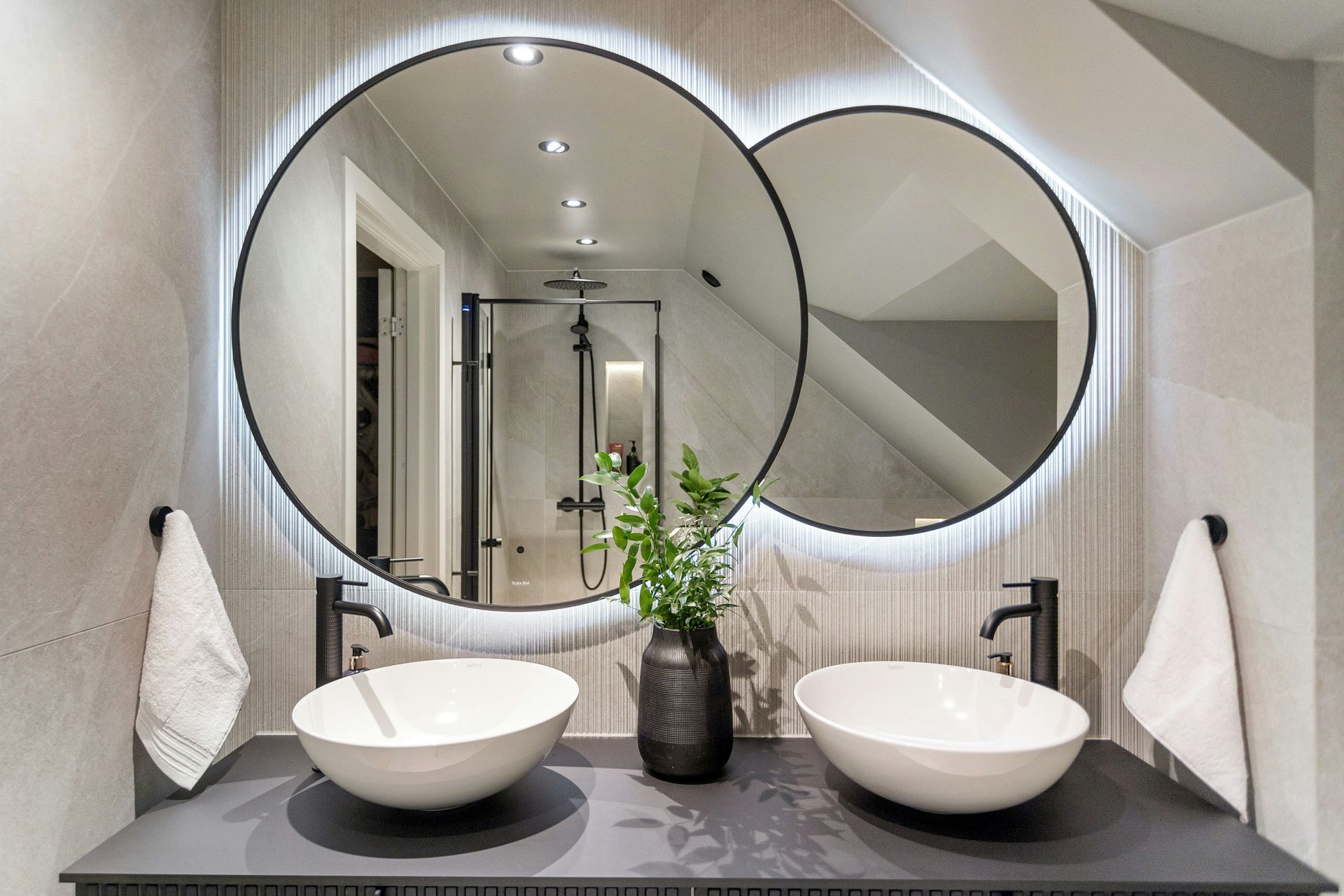 Double sink vanity with round mirrors, vessel sinks, and modern lighting in a luxury master bath design.